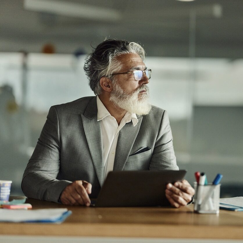 Mature businessman brainstorming while working on a computer in the office. Copy space.