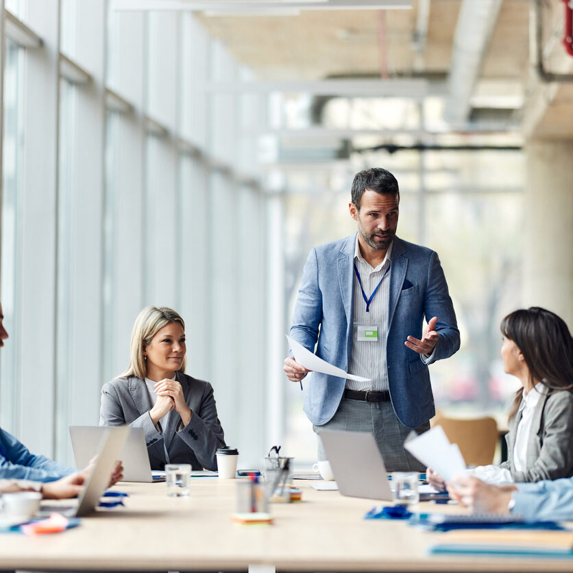 Mid adult male CEO communicating with group of his colleagues during a meeting in the office.